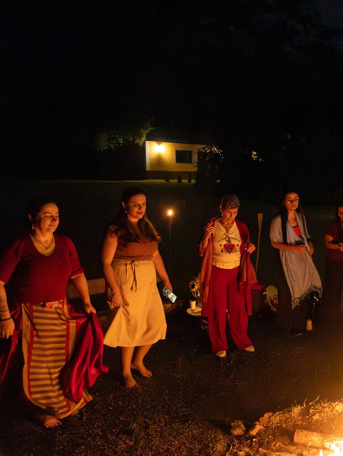 Mulheres dançando ao redor do fogo à noite